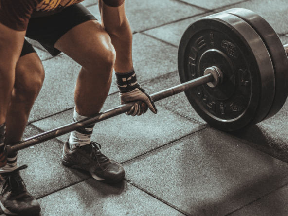 A person performing a deadlift with a barbell loaded with heavy weights on a gym floor. The scene highlights strength training and weightlifting exercises, common activities in fitness franchises. Title: Strength Training at a Fast-Growing Intimate Fitness Franchise